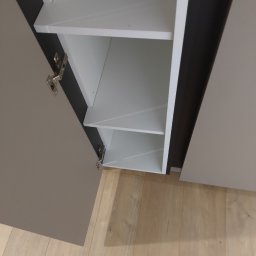 Griffin House - Otwarta szafka z półkami w odcieniach szarości i bieli, widoczne zawiasy, na podłodze panele w Białymstoku.
