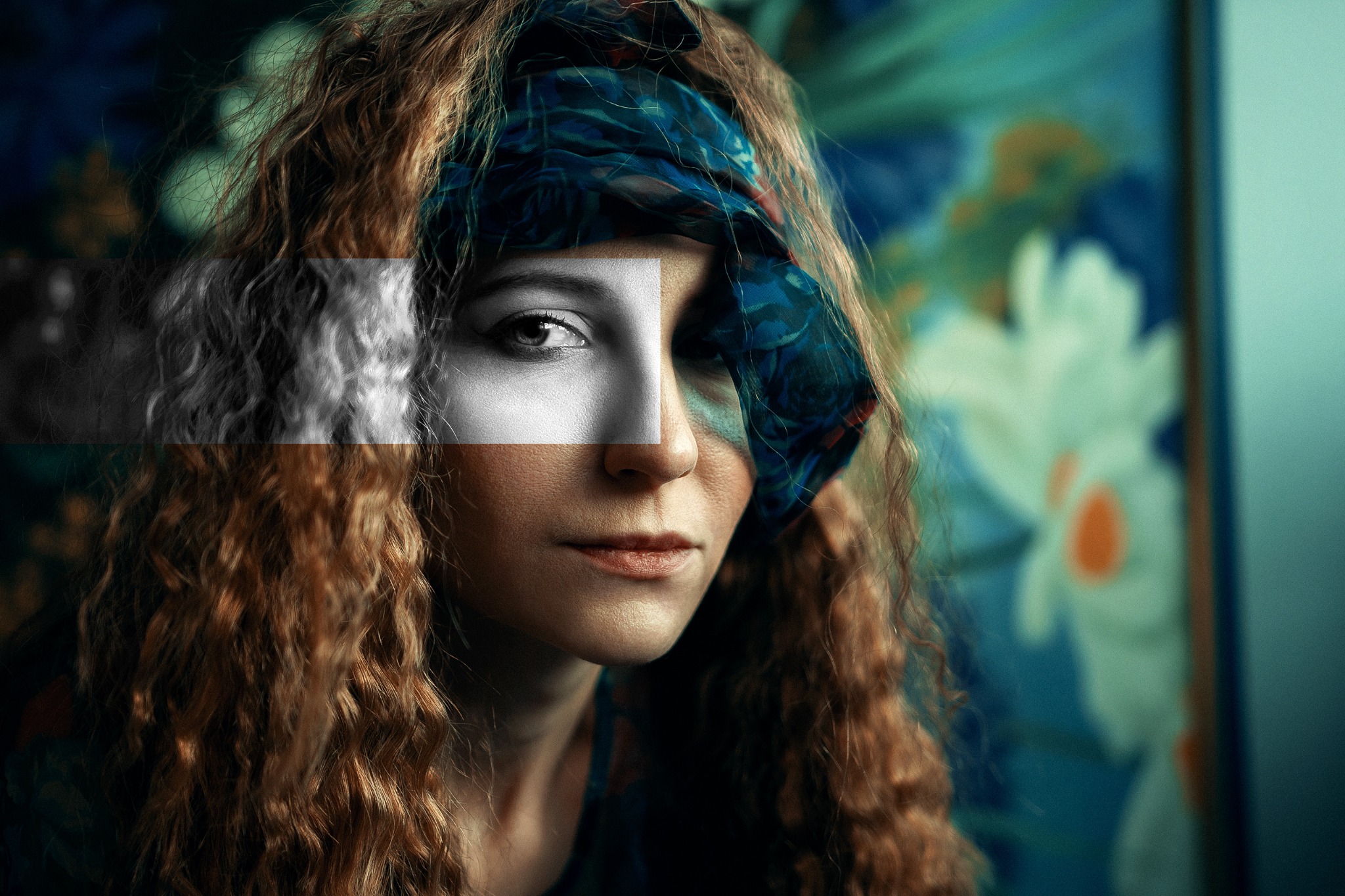 Portret kobiety z kręconymi włosami i chustą na głowie, z fragmentami twarzy w odcieniach szarości, na rozmytym tle z motywem kwiatowym.