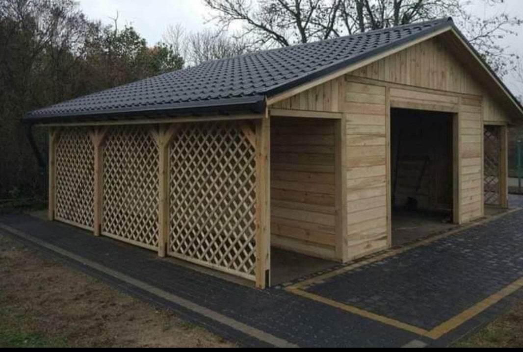 Zadaszona drewniana konstrukcja z kratownicą i czarnym dachem z blachodachówki, otoczona kostką brukową.