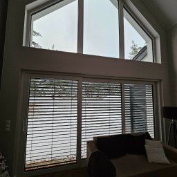 Pentra Plus - Wnętrze z dużym oknem z żaluzjami poziomymi i trójkątnym oknem powyżej, widok na zaśnieżony krajobraz. Minimalistyczny design, stonowana kolorystyka.