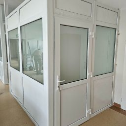 Pentra Plus - Biała, przeszklona konstrukcja z drzwiami, prawdopodobnie biurowa, z widoczną osobą pracującą wewnątrz. Widoczne detale wykończenia i oświetlenie.