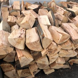 Drewno Kominkowe Żywiec - Kłody pociętego drewna ułożone w skrzyni samochodu dostawczego, widoczne fragmenty kory na niektórych kawałkach.