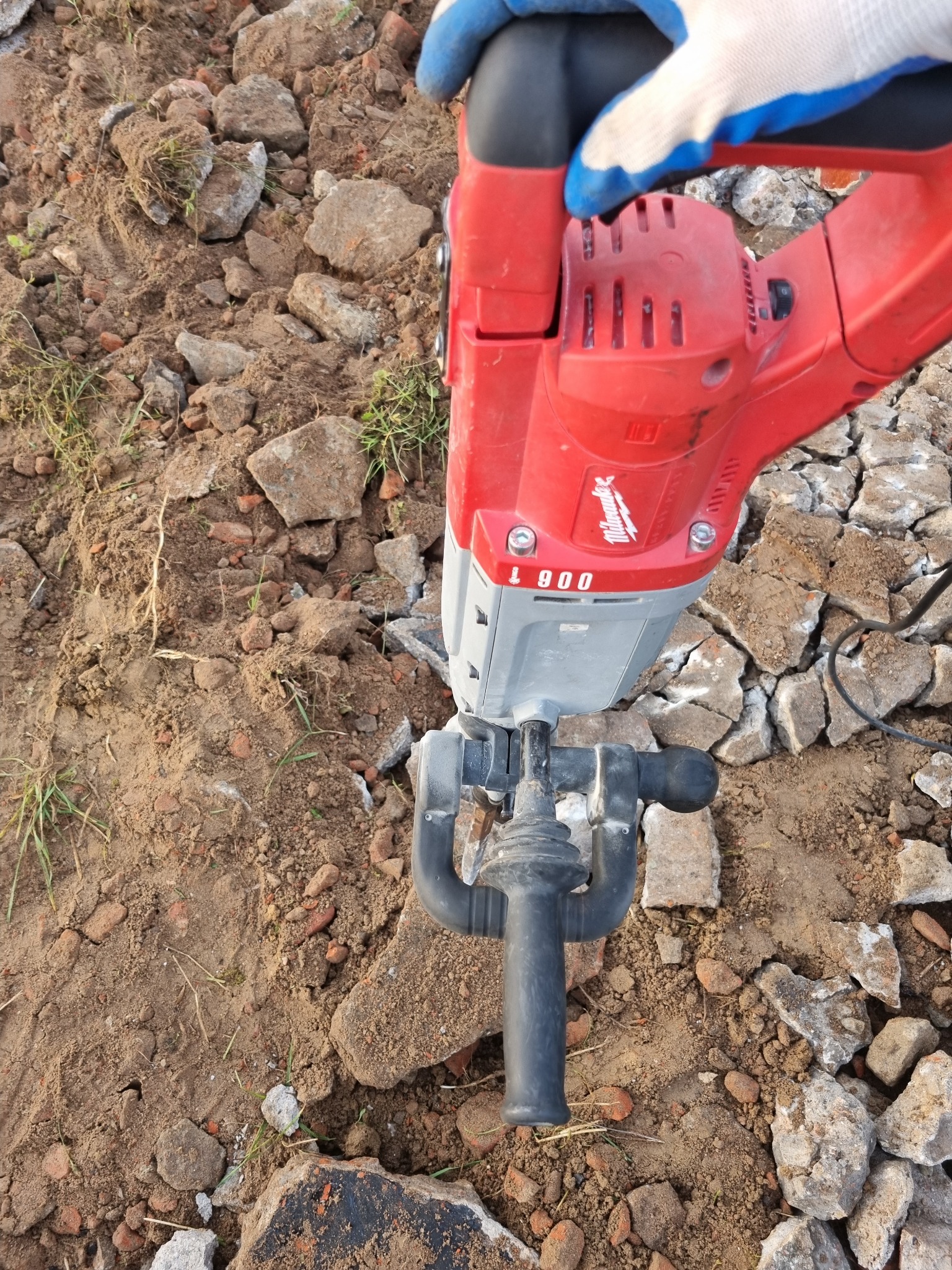 Praca z młotem udarowym Milwaukee w Tucholi przy rozbijaniu gruzu i utwardzonej ziemi, widoczna rękawica robocza.