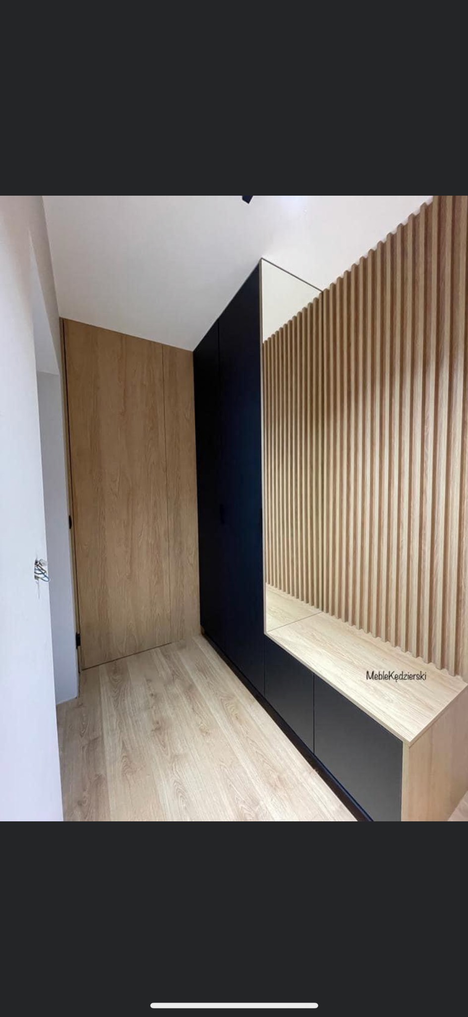 Nowoczesna zabudowa przedpokoju z szafą z drewnopodobnymi frontami, czarnymi szafkami i ścianą z drewnianych lameli z lustrem.