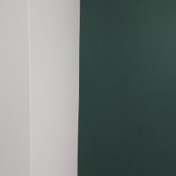 Pro-rem uslugi remontowe - Fragment ściany po malowaniu, z wyraźnym podziałem na świeżo pomalowaną, białą część i ciemnozieloną, matową powierzchnię.