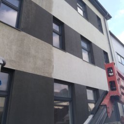 SOLARCELL - Mycie elewacji budynku z wyraźnym kontrastem czystej i brudnej powierzchni, widoczny podnośnik koszowy.