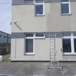 SOLARCELL - Elewacja budynku biurowego z aluminiową drabiną opartą o ścianę, widoczne ślady po myciu na kostce brukowej i wąż ciśnieniowy.