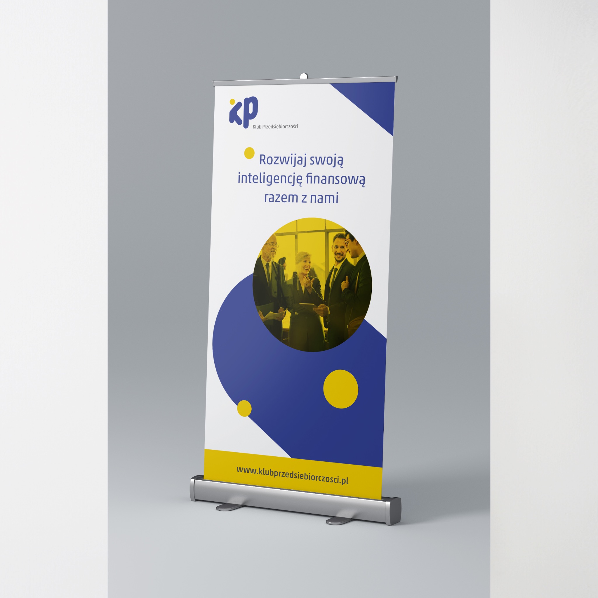 Roll-up reklamowy z logo i hasłem 'Rozwijaj swoją inteligencję finansową razem z nami' oraz zdjęciem grupy biznesmenów, widoczny adres strony internetowej.