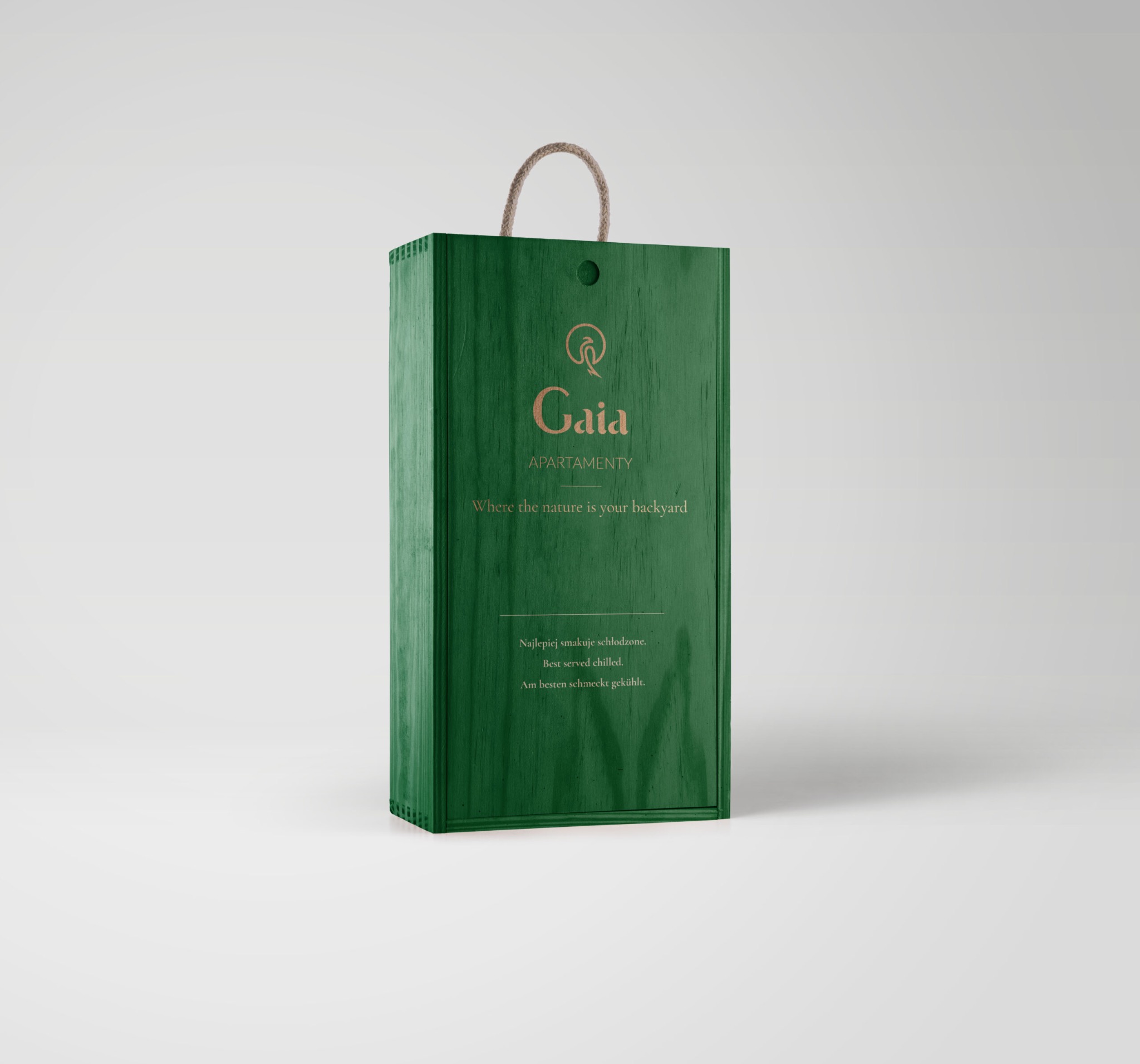 Zielone, drewniane pudełko z logo Gaia Apartamenty, z uchwytem ze sznurka, na białym tle.