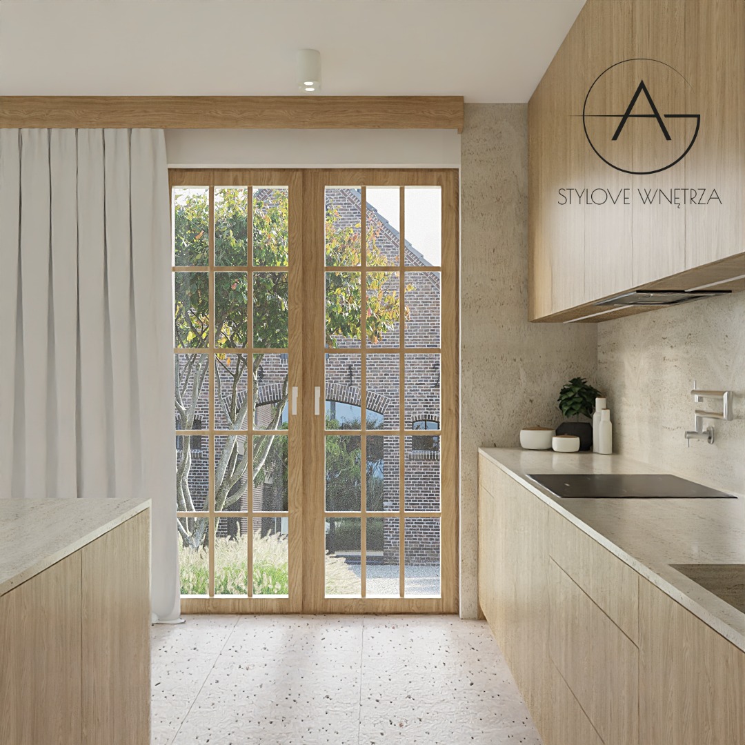 Jasna kuchnia z drewnianymi frontami i oknem z widokiem na ceglany budynek. Minimalistyczny design, kamienny blat, designerska bateria ścienna, logo firmy na szafce.