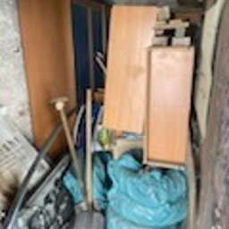 Wywóz Śmieci Gruzu Gabarytów - Wnętrze busa wypełnione meblami, deskami i workami z odpadami, widoczne narzędzia - łopata i prawdopodobnie grabie. Chaos i brak segregacji.