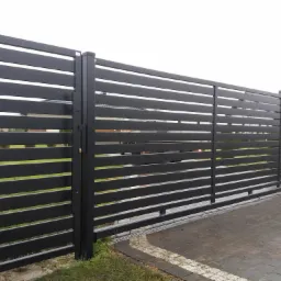 Nowoczesna, przesuwna brama wjazdowa z poziomych, metalowych profili, pomalowana na ciemny kolor, widoczna z zewnątrz posesji, na tle kostki brukowej i trawnika.