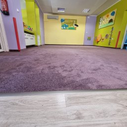Pro-Tech - Fioletowa, pluszowa podłoga w pustym przedszkolu z kolorowymi ścianami i dekoracjami.
