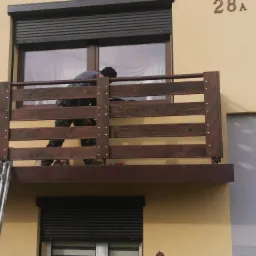 Montaż nowej, poziomej konstrukcji z desek na balkonie w Mszanie Dolnej, widoczna drabina i narzędzia.