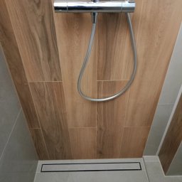 ProArt4you - Nowoczesna kabina prysznicowa walk-in z odpływem liniowym i panelami ściennymi imitującymi drewno, chromowana armatura.