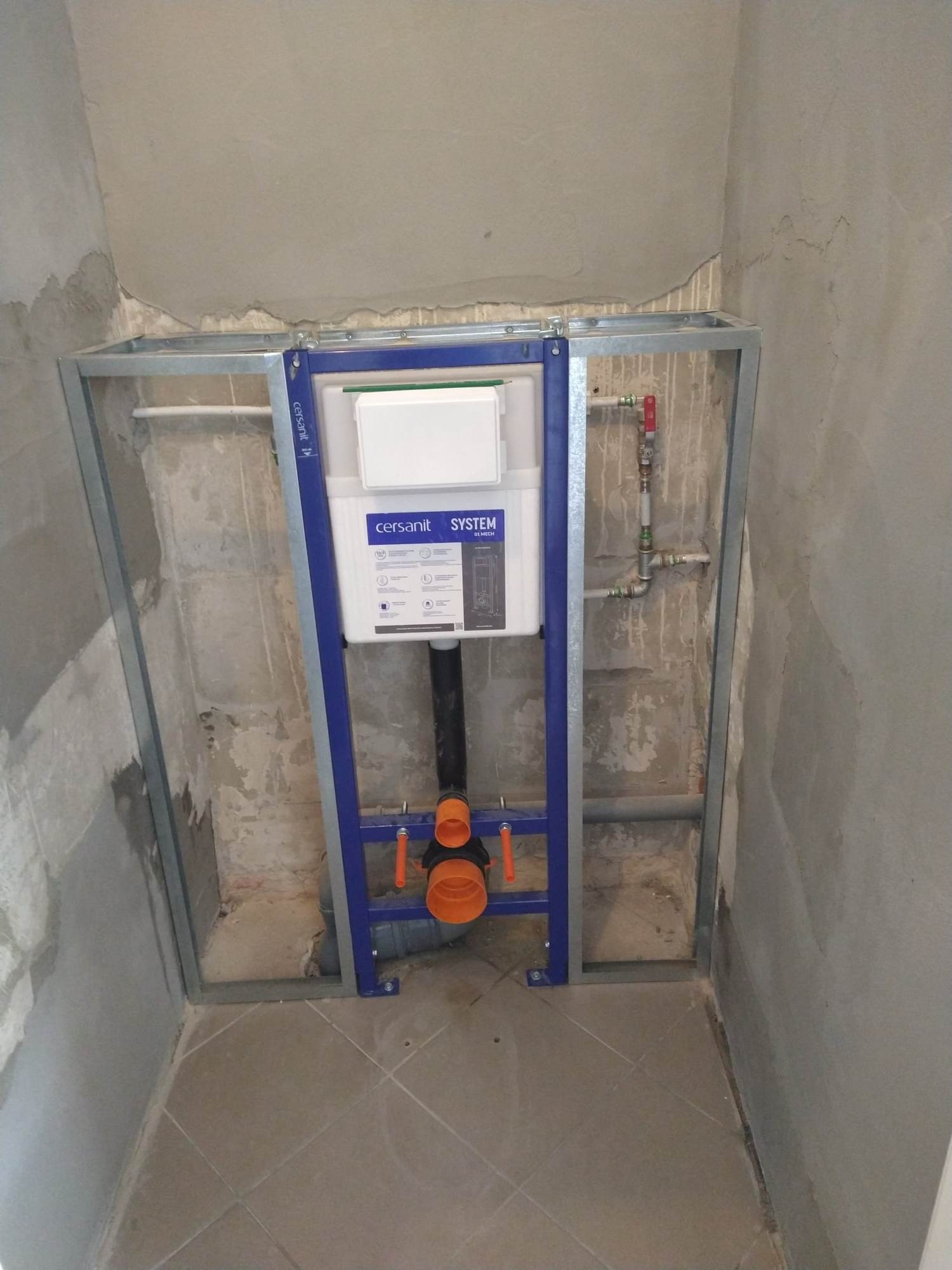 Stelaż podtynkowy Cersanit w trakcie montażu w surowej łazience, widoczne instalacje wodne i kanalizacyjne, ściany w stanie deweloperskim przed wykończeniem.