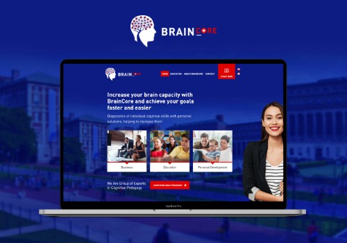 Laptop MacBook Pro wyświetla stronę internetową BrainCore z uśmiechniętą kobietą w marynarce po prawej stronie ekranu; w tle rozmytym budynek.