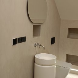 dominik florczak - Minimalistyczna łazienka w Łodzi z beżowymi ścianami, okrągłym lustrem, umywalką na postumencie i podwieszaną toaletą z podświetleniem LED w niszy.