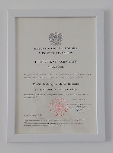 Oprawiony w białą ramkę certyfikat księgowy Ministra Finansów Rzeczypospolitej Polskiej, wydany dla Katarzyny Marii Rapuchy, z datą 2014-09-15, z widocznym orłem w koronie i pieczęcią.