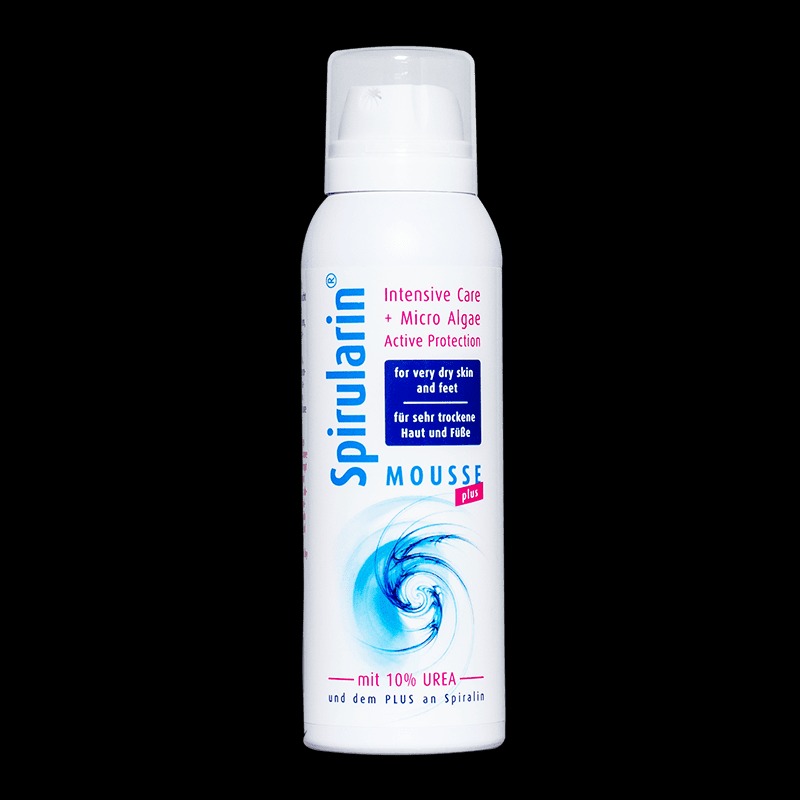 Biała butelka pianki Spirularin Mousse Plus z 10% mocznikiem, przeznaczona do pielęgnacji bardzo suchej skóry dłoni i stóp, na czarnym tle.