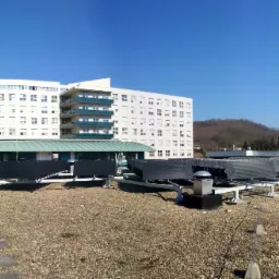 Rząd kolektorów słonecznych na płaskim dachu budynku szpitalnego w słoneczny dzień.