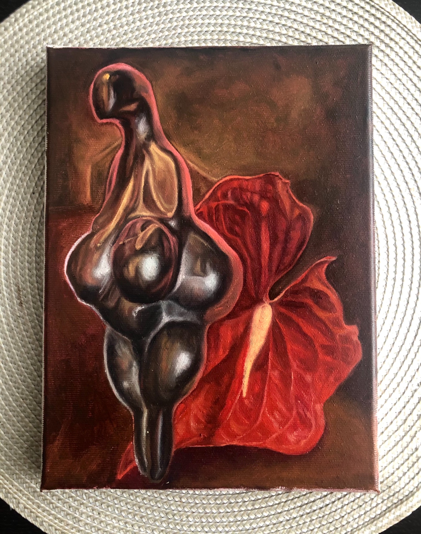 Olejny obraz na płótnie przedstawiający stylizowaną figurę kobiety w odcieniach brązu i szarości, obok czerwonego kwiatu anturium na ciemnym tle.