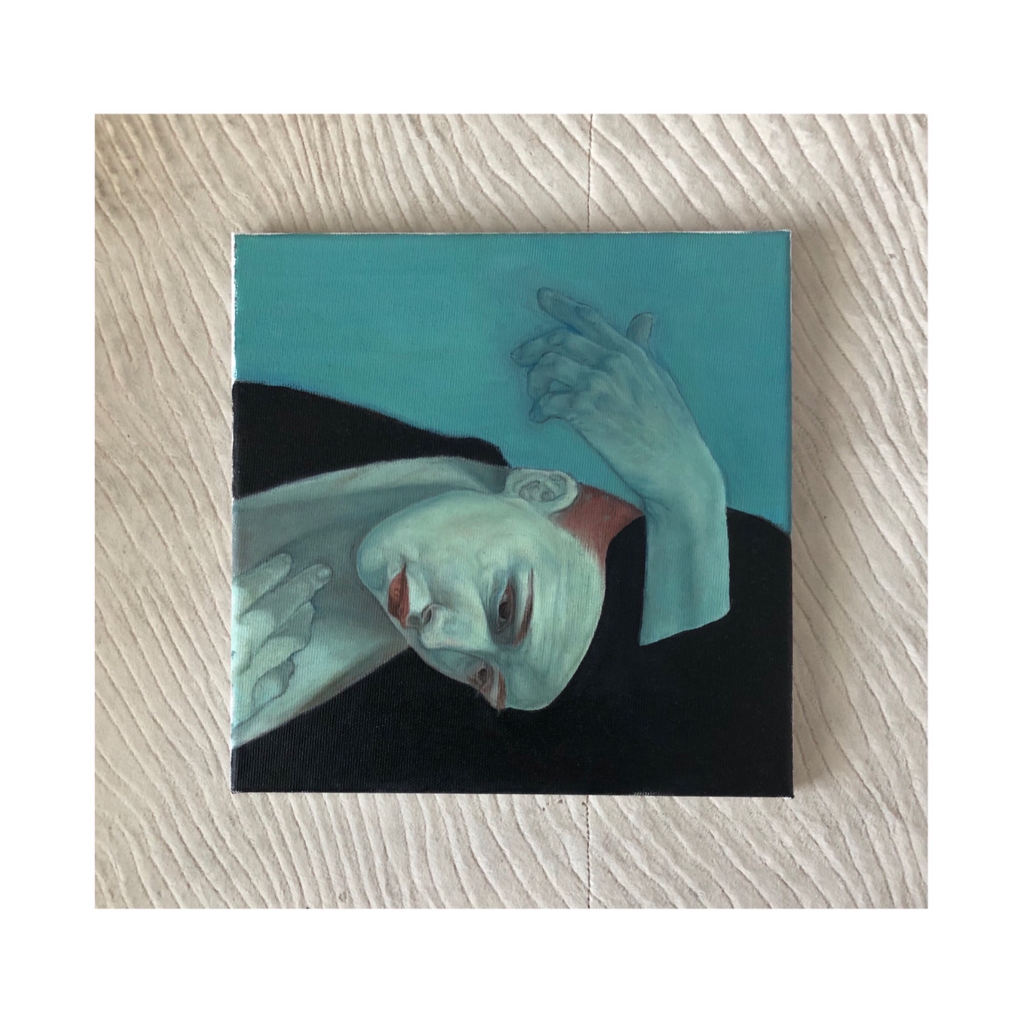 Portret kobiety w odcieniach błękitu i czerni, namalowany na płótnie, leżącym na teksturowanym tle.