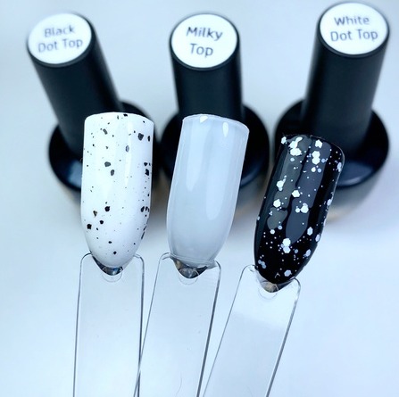 Prezentacja trzech odcieni lakierów do paznokci: biały z czarnymi kropkami, mleczny oraz czarny z białymi kropkami, na przezroczystych wzornikach, z buteleczkami lakierów w tle.