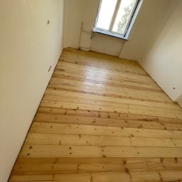 Project MasterWood Przemysław Bejmert - Wykończona podłoga z jasnego drewna w pokoju z oknem dachowym. Widoczne deski podłogowe po renowacji, z naturalnym rysunkiem drewna i połyskiem lakieru.