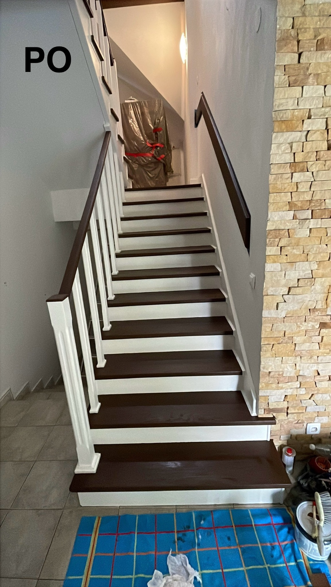 Odnowione schody dębowe w stylu angielskim. Białe podstopnie i balustrady kontrastują z ciemnymi stopniami i poręczami. Widoczna ściana z dekoracyjną okładziną.