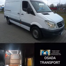 Biały samochód dostawczy Mercedes Sprinter na parkingu, widok z boku, z otwartymi tylnymi drzwiami prezentującymi oświetloną przestrzeń ładunkową z drewnianą podłogą; w tle ulotka reklamowa firmy...