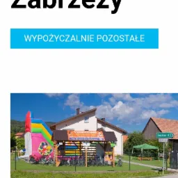Wypożyczalnia rowerów i atrakcji dla dzieci przy ścieżce Velo Dunajec, widoczny kolorowy dmuchany zamek oraz rząd rowerów pod zadaszeniem.