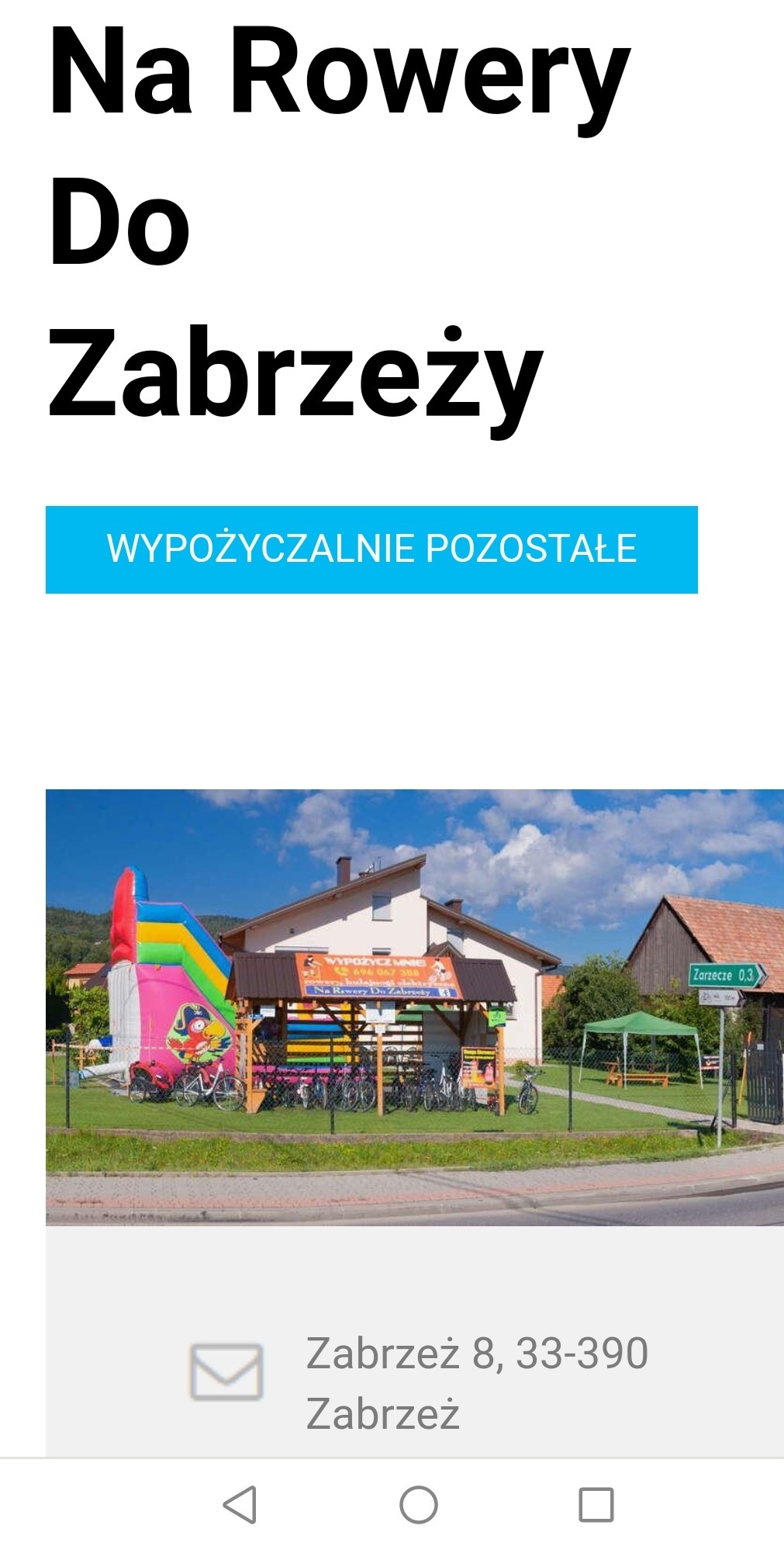 Wypożyczalnia rowerów i atrakcji dla dzieci przy ścieżce Velo Dunajec, widoczny kolorowy dmuchany zamek oraz rząd rowerów pod zadaszeniem.