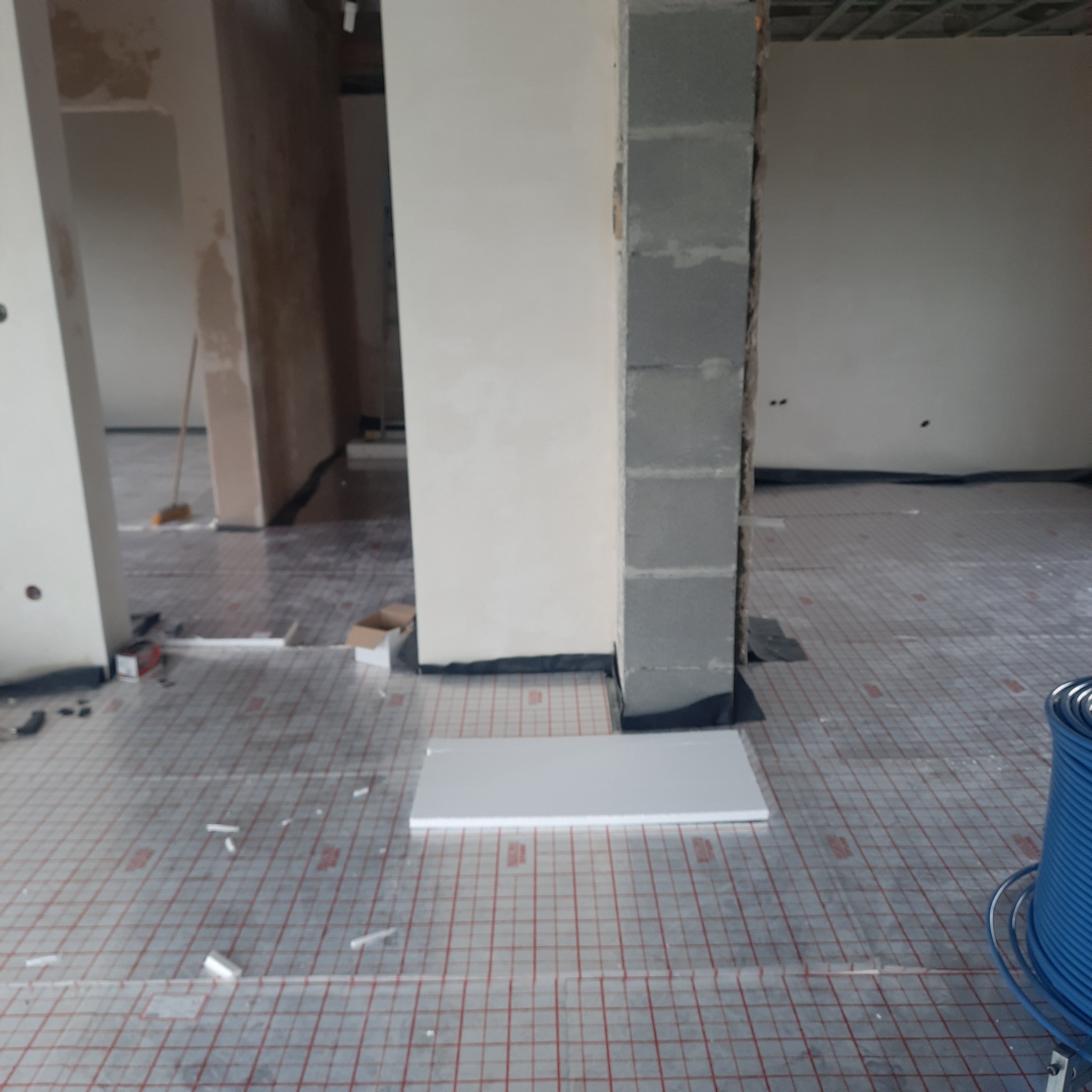 Podłogówka w trakcie montażu w Wałbrzychu: widoczne maty grzewcze z siatką, styropian, oraz zwój niebieskiego przewodu.