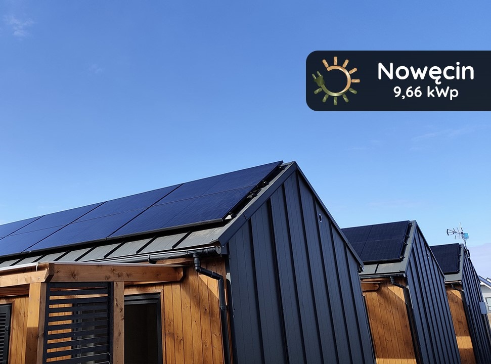 Panele fotowoltaiczne na dachu nowoczesnego domu z drewnianą elewacją, błękitne niebo w tle, logo firmy Nowęcin 9,66 kWp w prawym górnym rogu.