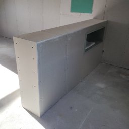 KS Kajetan Sobel - Konstrukcja z płyt kartonowo-gipsowych z wnęką, zamontowana w pomieszczeniu w trakcie prac wykończeniowych w Poznaniu. Widoczne ślady po wkrętach na powierzchni płyt.