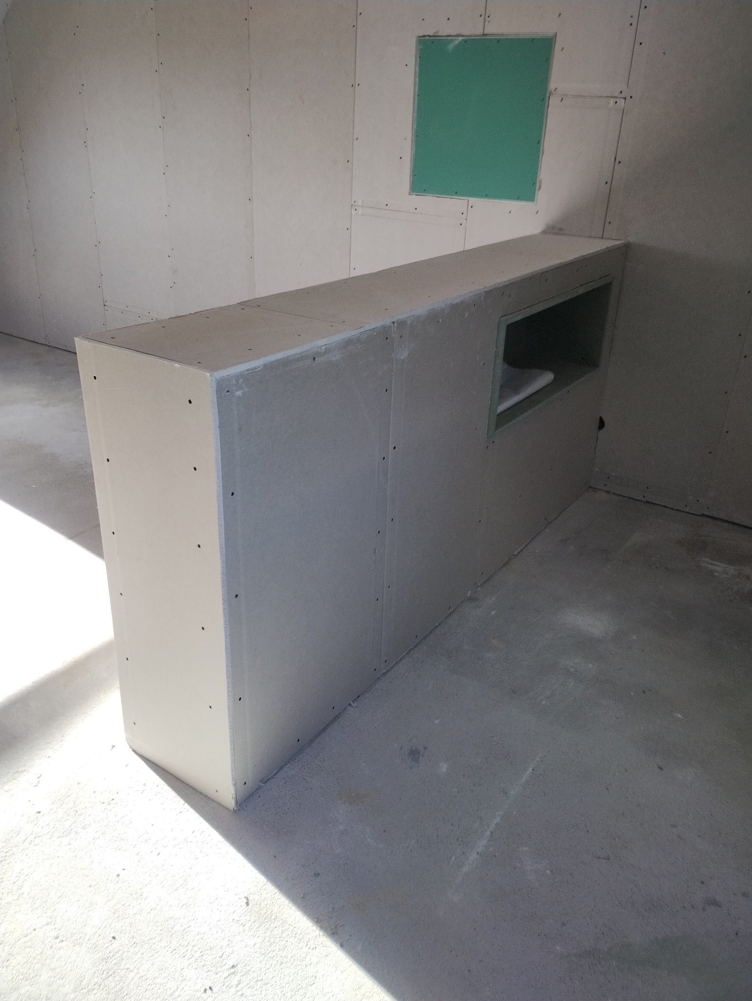 Konstrukcja z płyt kartonowo-gipsowych z wnęką, zamontowana w pomieszczeniu w trakcie prac wykończeniowych w Poznaniu. Widoczne ślady po wkrętach na powierzchni płyt.