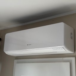 Soplo Klimatyzacja - Biała jednostka klimatyzacji Fuji Electric zamontowana nad białymi drzwiami w pomieszczeniu o jasnych ścianach. Widoczne logo producenta i panel sterowania.