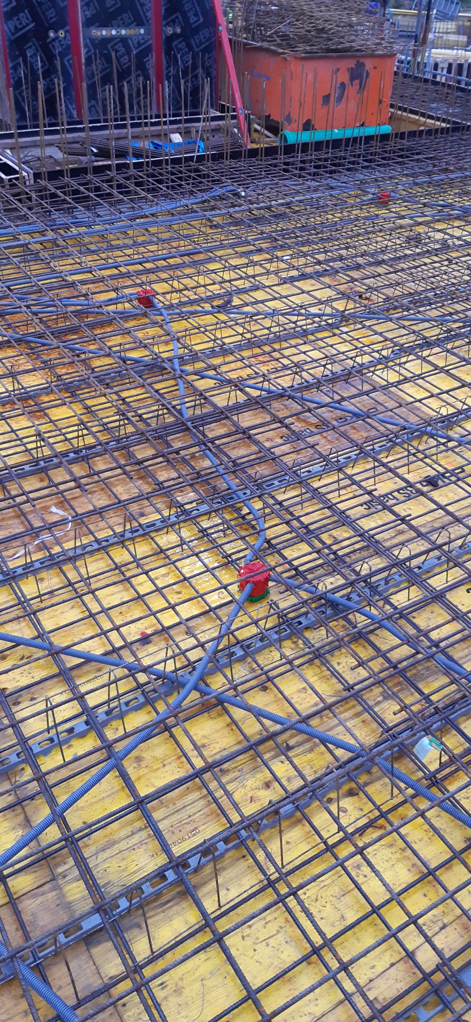 Zbrojenie płyty fundamentowej z rurami instalacji elektrycznej i puszkami podtynkowymi, widok z góry.