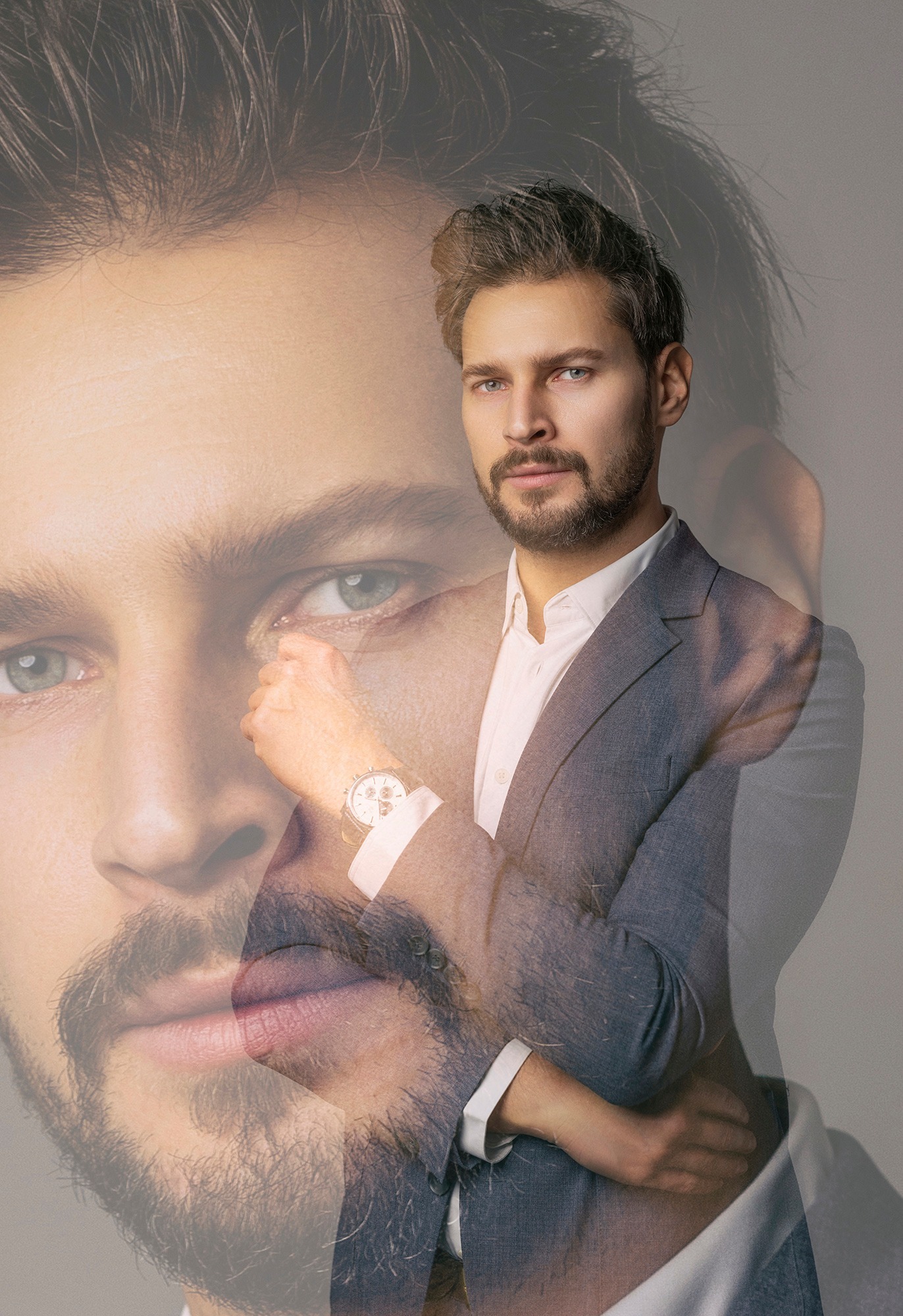 Portret mężczyzny w garniturze z nałożoną półprzezroczystą twarzą, eksponujący zegarek na nadgarstku.