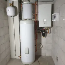 Instalacja grzewcza z zasobnikiem i kotłem gazowym marki Panasonic w pomieszczeniu kotłowni w Miliczu, widoczne rury miedziane i elementy armatury.