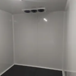 Wnętrze chłodni z trzema wentylatorami chłodzącymi zamontowanymi pod sufitem i oświetleniem jarzeniowym.