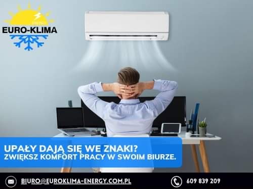 Mężczyzna siedzi zrelaksowany przy biurku w biurze, nad nim zamontowany klimatyzator, logo firmy w lewym górnym rogu.