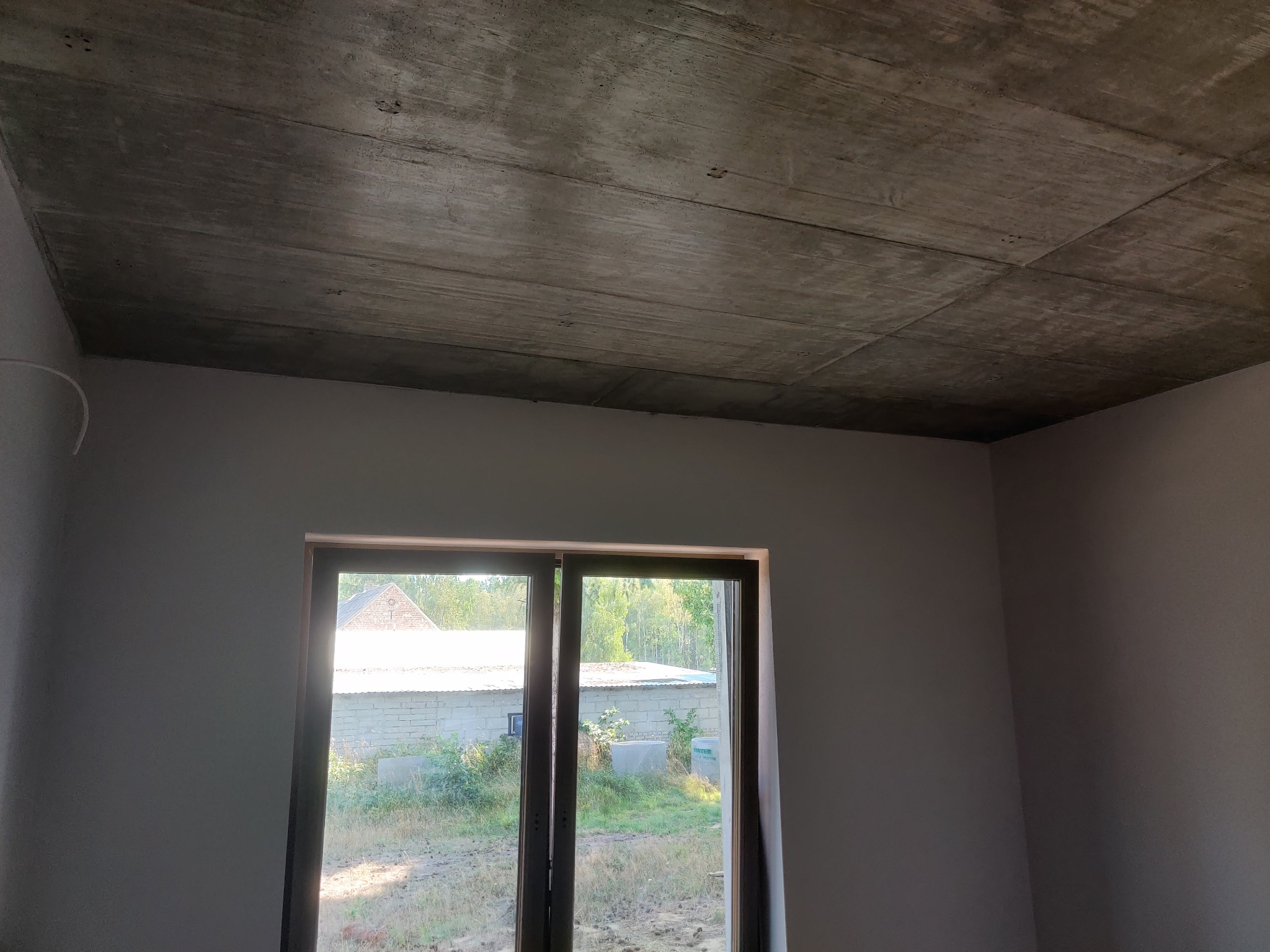 Surowy betonowy strop w nowym budynku z widokiem na zewnątrz przez okno