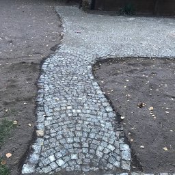 Usługi Brukarsko-Ziemne Oleh Berezovskyi - Ścieżka z małej kostki granitowej, układana łukiem na ziemi z opadłymi liśćmi, widok z góry, częściowo ukończona.