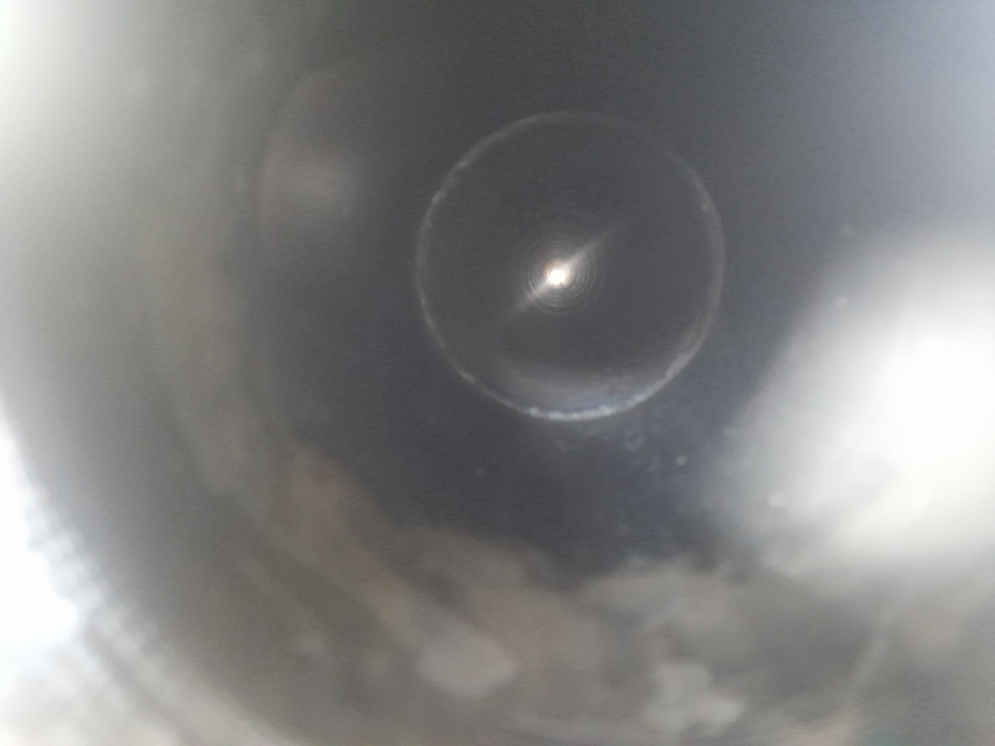 Wnętrze rury ze stali nierdzewnej, widok od środka z silnym odbiciem światła na końcu.