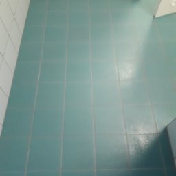 M-J CLEAN - Turkusowe płytki podłogowe w łazience, widoczny fragment wanny z hydromasażem w tle.