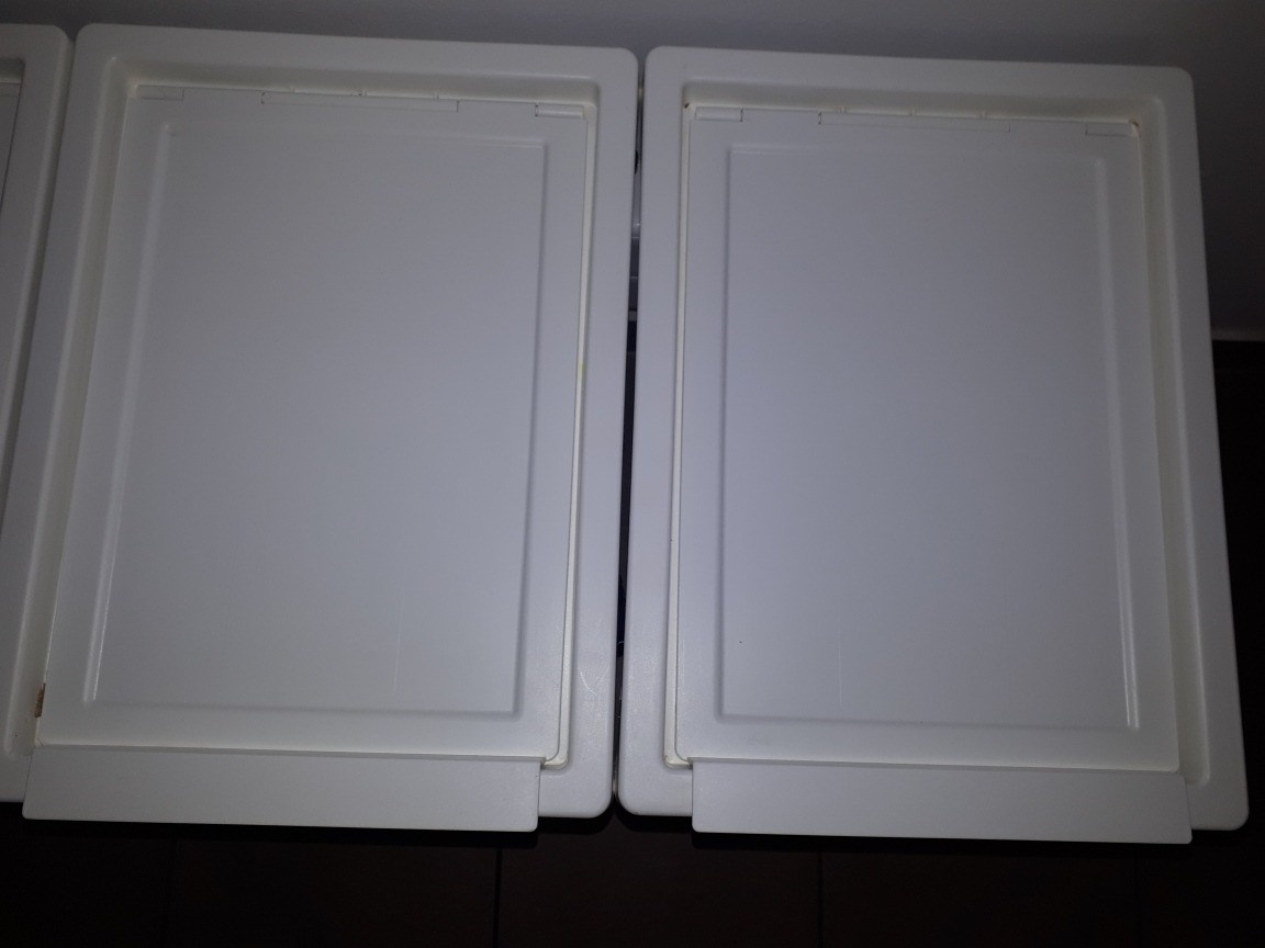 Dwie białe, zamknięte szafki z prostymi, ramowymi frontami i wystającymi uchwytami, widziane z góry pod lekkim kątem.