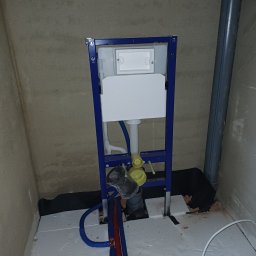 MSJ Instal Marcin Jurkowski - Stelaż podtynkowy Geberit Duofix z widocznymi rurami doprowadzającymi wodę i odpływowymi, zamontowany na podłodze z izolacją, przy surowej ścianie.