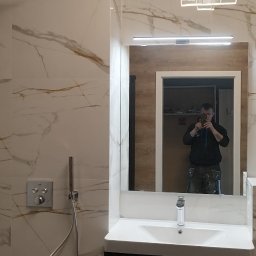 Pietras - Nowoczesna łazienka z marmurowymi płytkami, deszczownicą i umywalką z szafką w kolorze czarnym. W lustrze odbija się osoba robiąca zdjęcie.